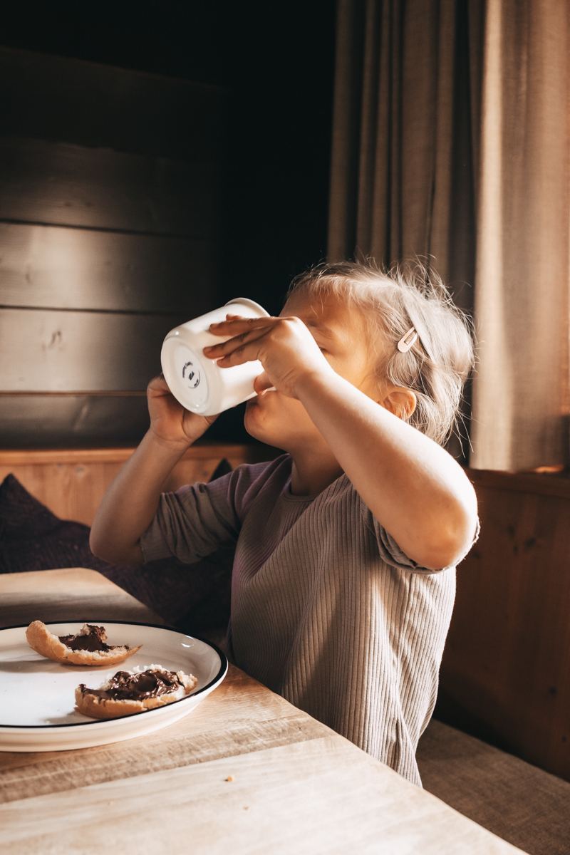 Mädchen trinkt Kakao am Frühstückstisch